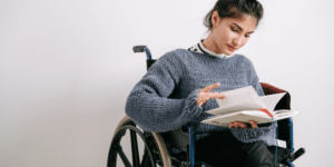 person in wheelchair flipping book to learn ndis goal and rules