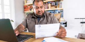 a person with disability checking a document and writing on laptop