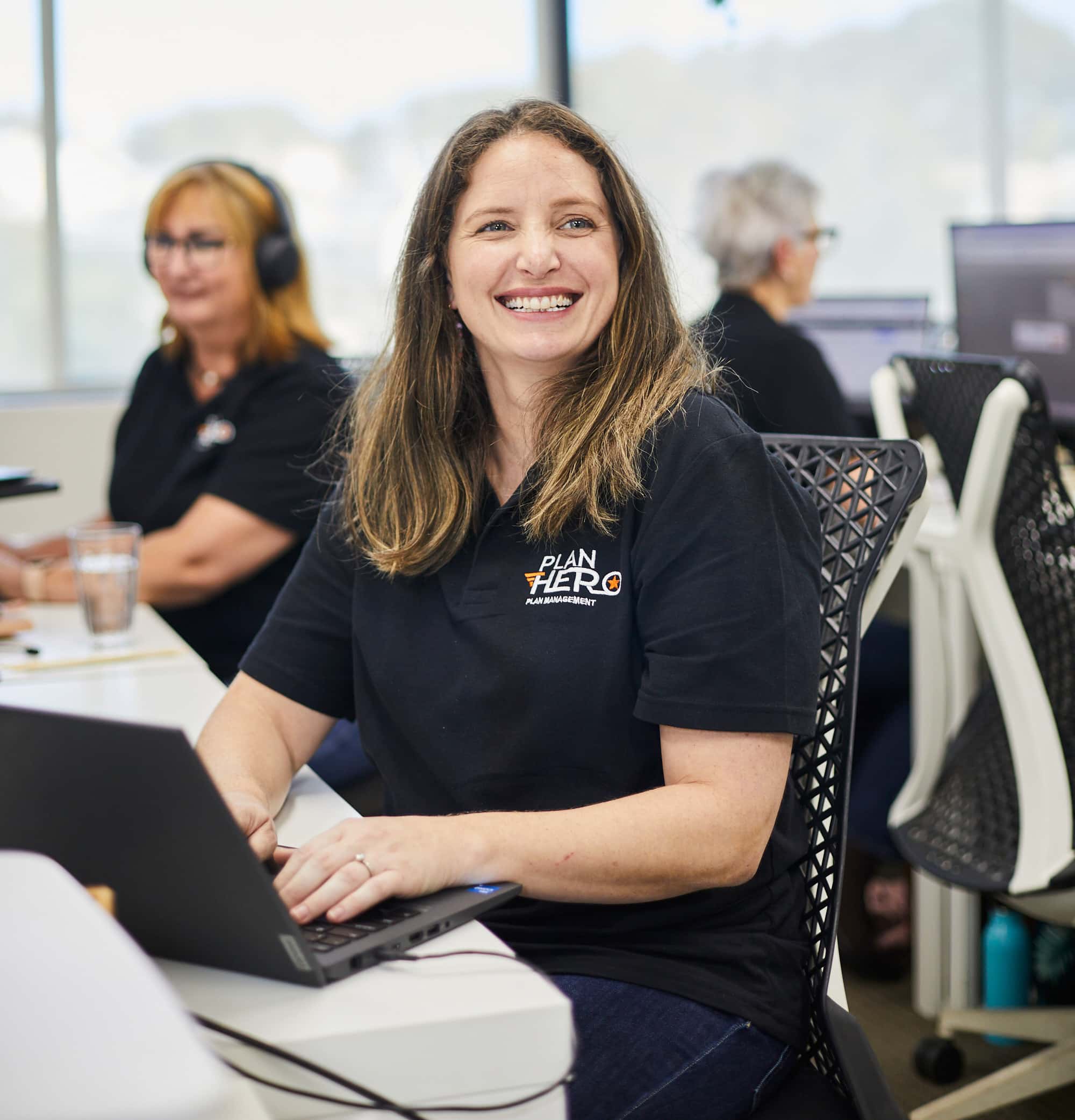 Plan Manager sitting at a desk smiling with joy on her face